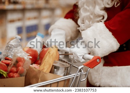 Santa Claus doing grocery shopping at the supermarket, he is pushing a full shopping cart, hands close up