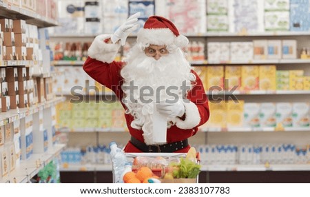 Shocked Santa Claus at the supermarket, he is checking a long expensive grocery receipt Royalty-Free Stock Photo #2383107783