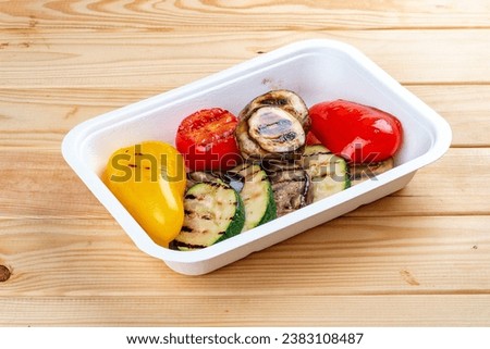 Grilled vegetables. Healthy diet. Takeaway food. Eco packaging. On a wooden background.