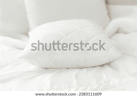 White quilted cotton pillow on a white bedding white background. Cushion. Home textile. Close up photo
