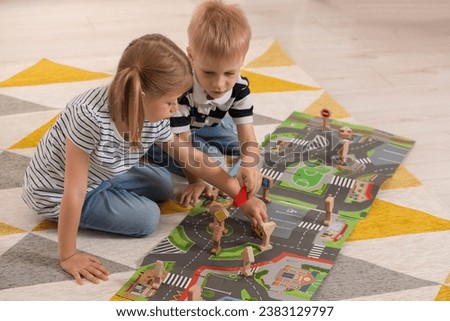 Little children playing with set of wooden road signs and toy cars indoors