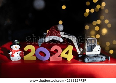 multi-colored numbers 2024, toy mini excavator, souvenir snowman, bokeh. Christmas holidays, festive mood. Happy New Year business greeting concept for construction companies