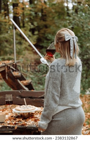 A young woman with a glass of wine has a picnic in the forest on an autumn day. High quality photo