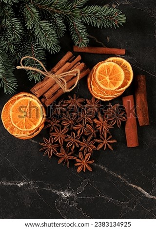 Christmas background with winter traditional spices to improve immunity during the cold period. Star anise, cinnamon and dried oranges and tangerines on a dark background with fir branches.
