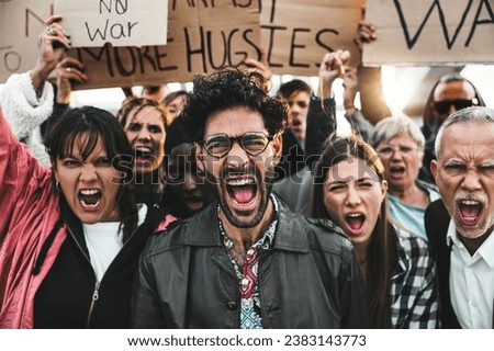 Group of multiracial peace activists walking on the street holding posters and banners - Diverse crowd of antiwar people protesting against war