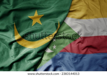 big waving national colorful flag of mauritania and national flag of comoros . macro