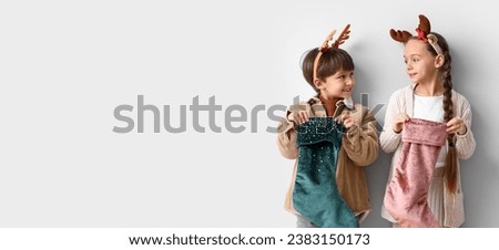 Cute little children with Christmas socks on light background with space for text