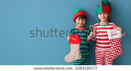 Cute little children in pajamas and with Christmas socks on blue background with space for text