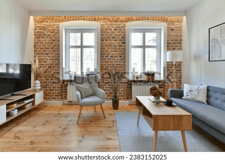 Renovated living room in the interior of an old tenement house, decorated in a classic style with exposed brick wall and a restored pine board floor with a place to rest.