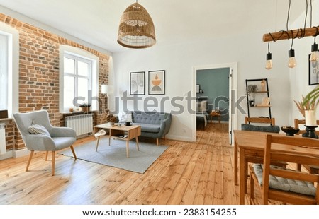 Renovated living room in the interior of an old tenement house, decorated in a classic style with exposed brick wall and a restored pine board floor with a place to rest and dining area