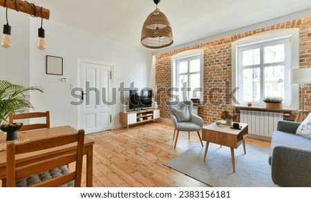 Renovated living room in the interior of an old tenement house, decorated in a classic style with exposed brick wall and a restored pine board floor with a place to rest and dining area