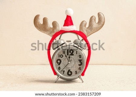 Alarm clock with Christmas reindeer horns on light background