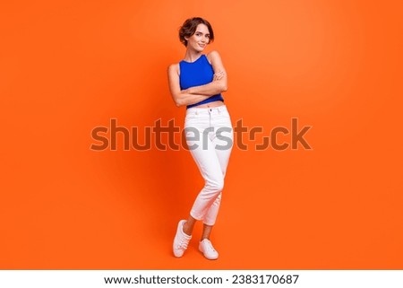 Full size portrait of lovely positive young girl crossed arms posing isolated on bright orange color background