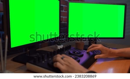 Closeup shot of man hands working at the desk using mixer editing video color settings, chroma key monitors .