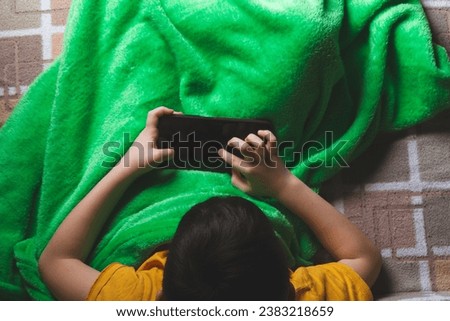 Phone in hands of child. Little boy playing mobile games on smartphone. Hand closeup..