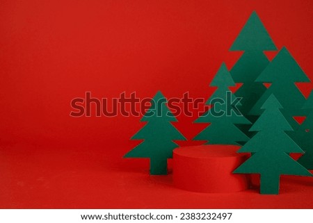 Christmas tradition background - red scene, cylinder podium mockup for presentation gifts, cosmetic products, good with green paper spruce forest, closeup. New year template for card, poster, flyer.
