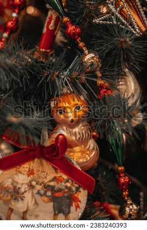 Vintage Christmas toy figurine of funny orange fox hanging on the Christmas tree branches with retro beads and decorations. New Year festive magic details