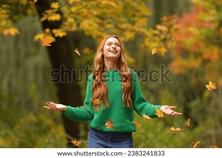 Autumn vibes. Happy woman throwing leaves up in park