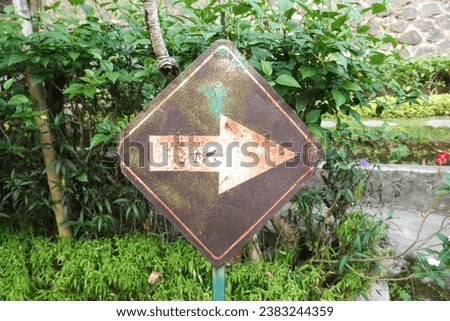 Weathered Turn Right sign on rusty colored board with garden backgrounds. White arrow turn right allowed sign. Royalty-Free Stock Photo #2383244359