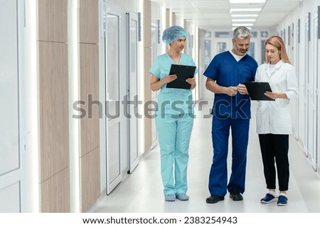 Medicine, healthcare and people concept. Surgeon and female doctor talking at hospital hallway. Medical team discussing a case.