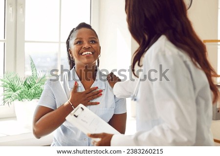 Happy female patient thanking her doctor from the bottom of her heart. Joyful, smiling, grateful, relieved, young African American woman holding hand on her chest and saying Thank you to physician