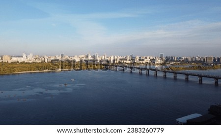 Aerial view of Kyiv cityscape with Dnipro river and bridge under clear blue sky