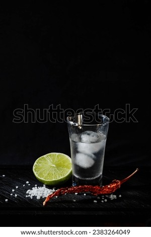 Mexican Tequila shots. Chilled alcoholic drink. Cold vodka. On a black background. With lime, pepper and salt on a dark background. space for text. concept luxury drink. Alcoholic drink concept