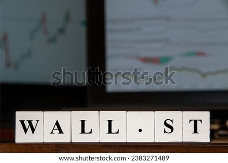 Financial image, "Wall. St" American markets in New York sign, The word's Wall St in front of two computer screens, displaying financial graphs.