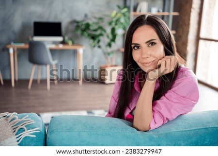 Photo of cheerful cute woman wear pink shirt sitting sofa smiling hand arm chin indoors apartment room