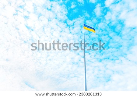 Bottom-up view of the national flag of Ukraine proudly flying against the backdrop of wispy altocumulus clouds in a deep blue sky.