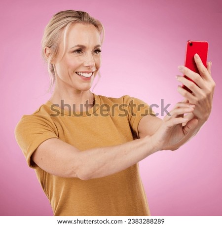 Selfie, happy and woman with a phone in the studio with a positive, optimistic and good mindset. Happiness, smile and female model from Canada taking a picture on a cellphone by a pink background.
