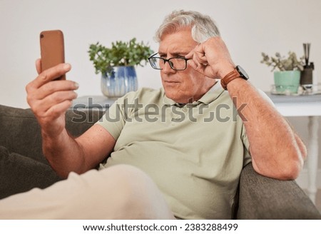 Phone, glasses and senior man reading a text message, blog or online news on a sofa in the living room. Vision, technology and elderly male person squinting while networking on a cellphone at home. Royalty-Free Stock Photo #2383288499