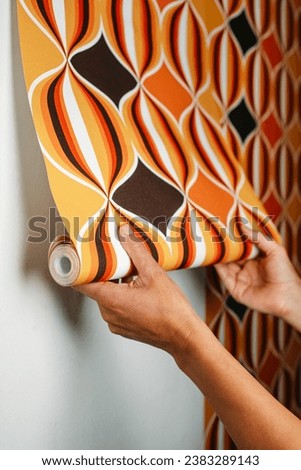 a caucasian man attaches a geometric patterned wallpaper to a white wall Royalty-Free Stock Photo #2383289143
