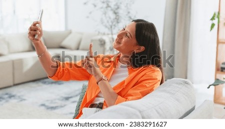 Happy, selfie and woman on sofa in living room, home or relax in apartment with peace on social media and app. Influencer, smile and post happiness online of photography on couch in house lounge
