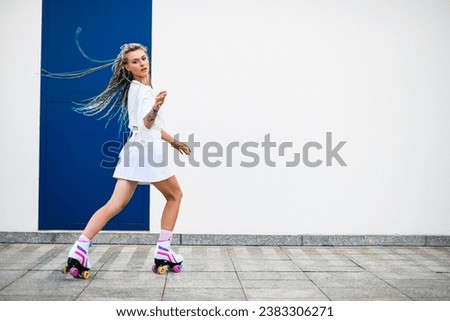 Young woman practicing rollerskating against white wall. Happy girl with rollerskates in the skating ground.Healthy lifestyle. Sport activity.