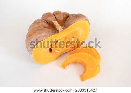 Half of a ripe orange pumpkin next to the pumpkin pulp, cut into thin slices, on a white background. Seasonal autumn dietary vegetables for a vegan or vegetarian diet. Ingredients for a healthy diet.