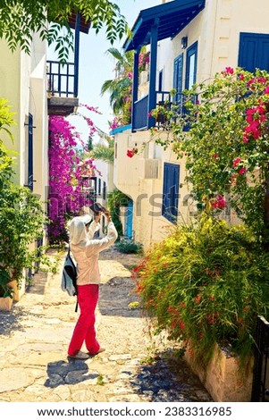 Woman takes picture of picturesque house on the street of Kalkan. Antalya Province, Turkey