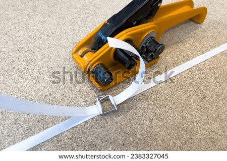 Manual packaging of cargo for shipping. Hand-operated polypropylene strapping tool. Packaging and shipping of goods packed in wooden crates.  Royalty-Free Stock Photo #2383327045