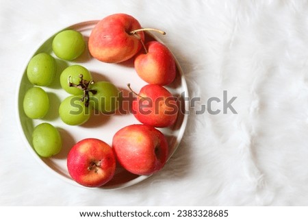 Apple strawberries and green grapes in white bowl isolated on white background.