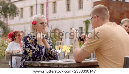 Guy is using his phone during the date. Checking messages, browsing the internet, or using it as a conversation starter or to share something interesting with girl. People lifestyle.