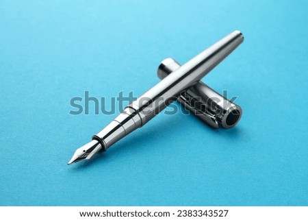 Stylish silver fountain pen with cap on light blue background, closeup Royalty-Free Stock Photo #2383343527