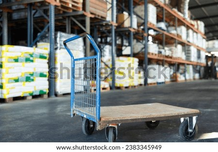 Empty platform hand truck standing in warehouse of construction hypermarket or garden store ready to transport goods Royalty-Free Stock Photo #2383345949