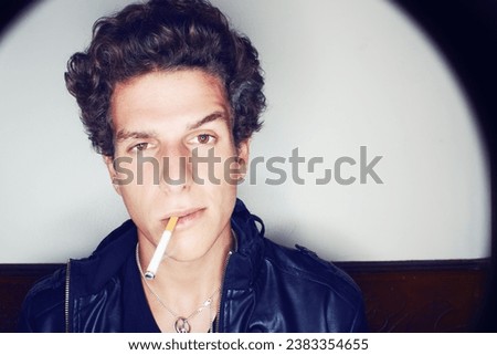 Portrait of man with cigarette, punk fashion and rockstar attitude on white background with spotlight. Cool rock style, modern creative and smoking, confident face of handsome male model in studio.