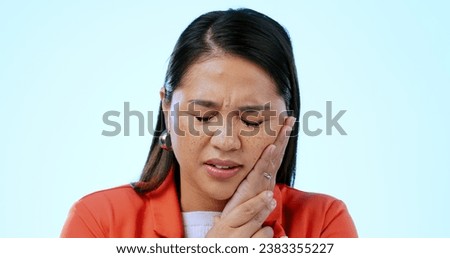 Pain, toothache and face of woman in studio for mouth injury, gum disease and oral gingivitis on blue background. Asian model with hands on cheek for dental crisis, sensitive teeth and jaw emergency Royalty-Free Stock Photo #2383355227