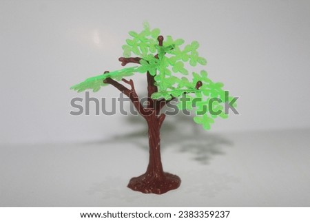 Nature in miniature: A plastic toy tree on a clean white canvas, where the beauty of the outdoors meets imagination