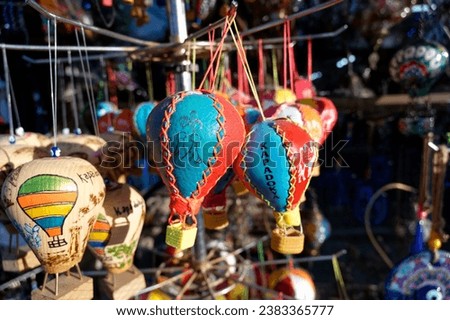 Vibrant array of souvenir balloons playfully bobbing in the breeze, set against the quaint charm of a local souvenir shop, awaiting their new owners