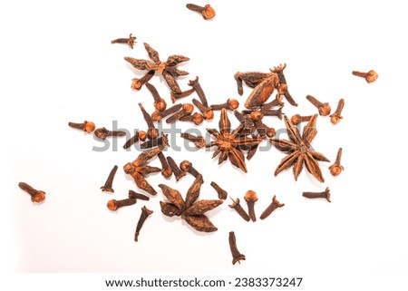 pile of dried cloves and heap of dried star anise in a white studio. cloves on a white background