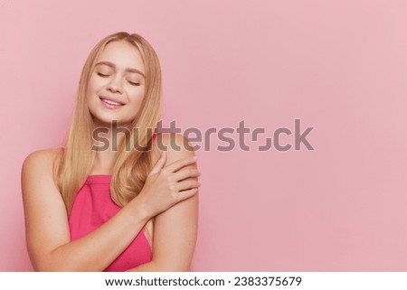 Pretty blonde girl in pink top poses isolated on pink backdrop with closed eyes and smile on her face, Beauty and Health concept, copy space