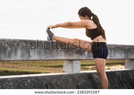 Asian woman warming up and stretching before running on a bridge in the morning in the sun,motion blur,concepts of running for good health.