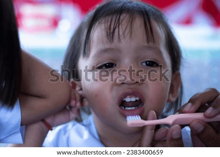 A caring mother gently brushes her little daughter's teeth for good dental health.